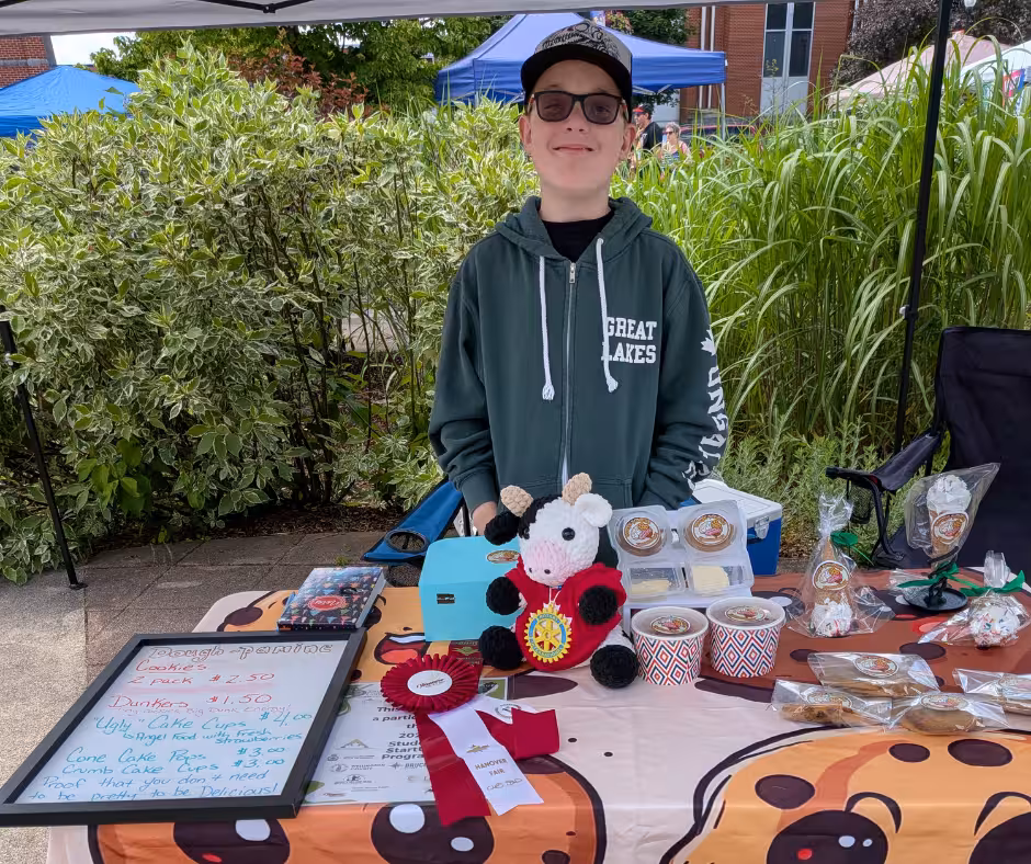 Young entrepreneur at a market display of crocheted goods.
