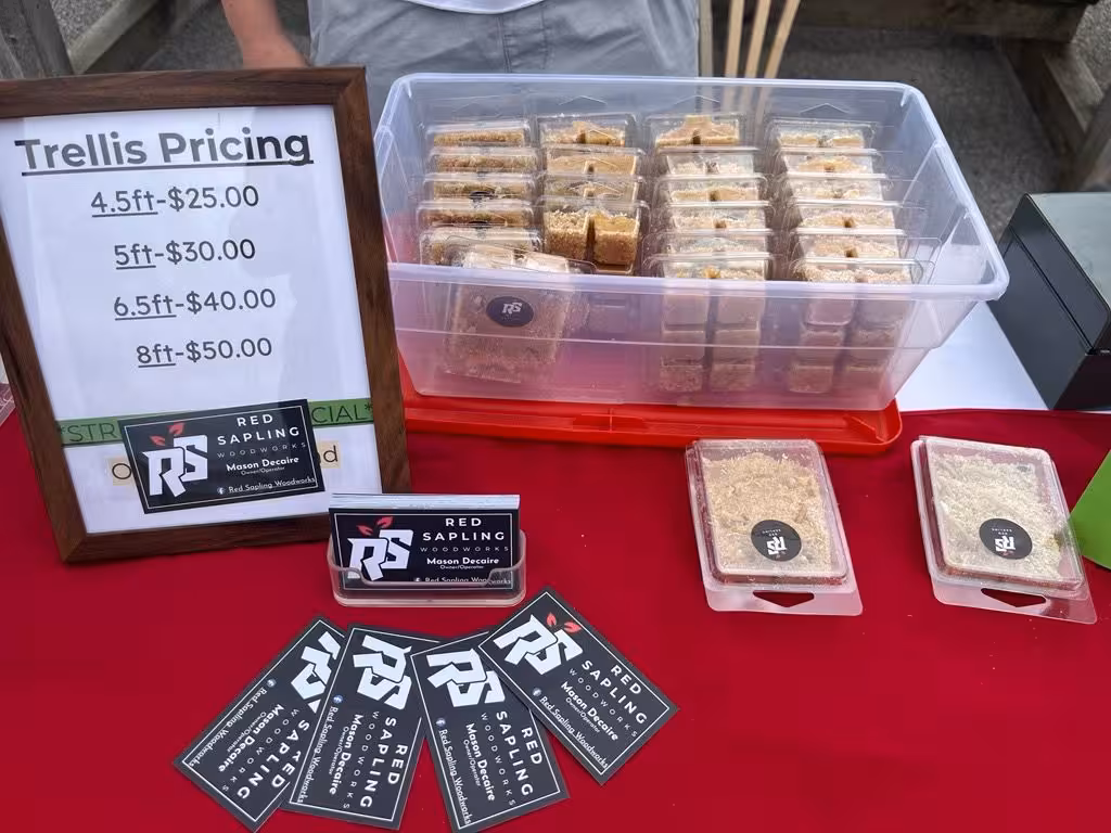 Wooden trellises and pricing at the Red Sapling Woodworks market display.