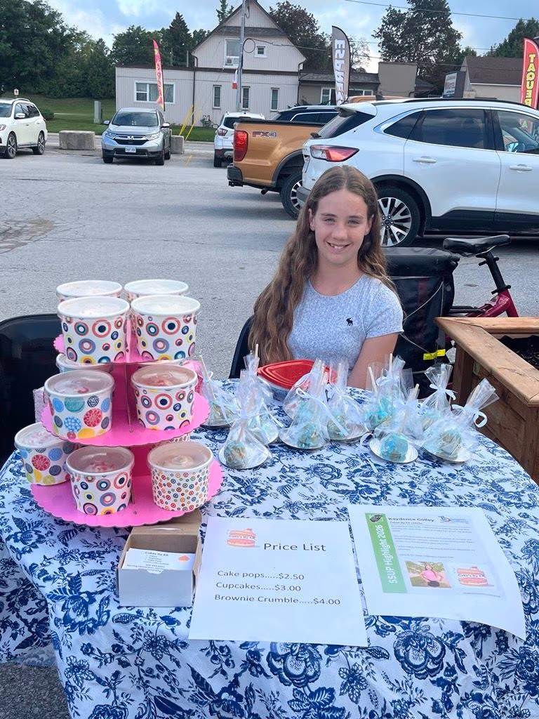 Cakes By KK baked goods and price list at a youth market.